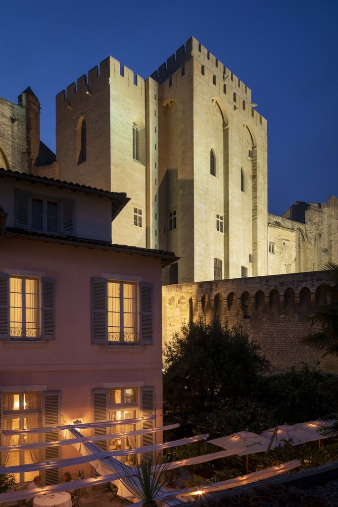 Elegant 18th-century French hotel with ornate stone facade, wrought iron balconies, and tall arched windows overlooking a cobblestone plaza