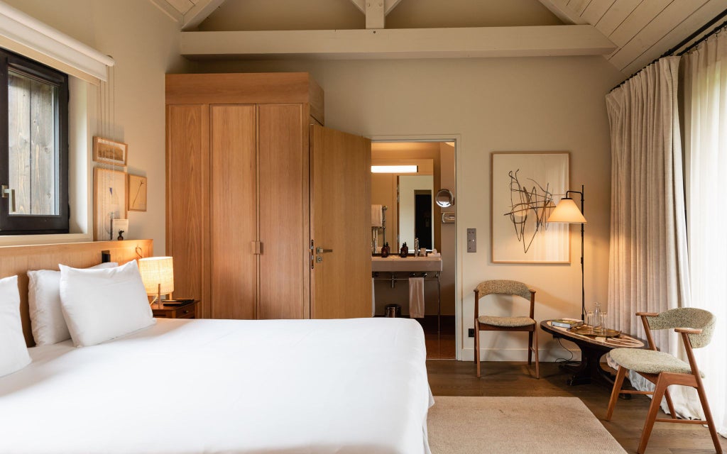 Elegant prestige room at Les Sources de Cheverny, showcasing plush white bedding, classic French decor, and soft natural light filtering through large windows