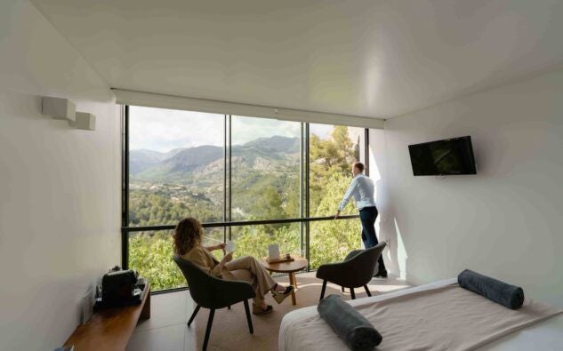 Minimalist wood-paneled suite with panoramic mountain views, sleek modern design, and floor-to-ceiling windows at VIVOOD Landscape Hotel in scenic Spain