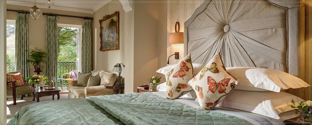 Elegant superior room at scenset Hotel Kenmare with plush white bedding, hardwood floors, and expansive windows overlooking lush Irish landscape