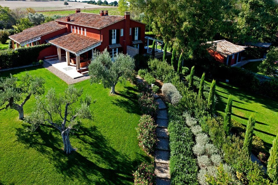 Rustic-chic Italian hotel room with soft beige linens, wooden furnishings, and warm terracotta-toned walls at Locanda Rossa boutique accommodation