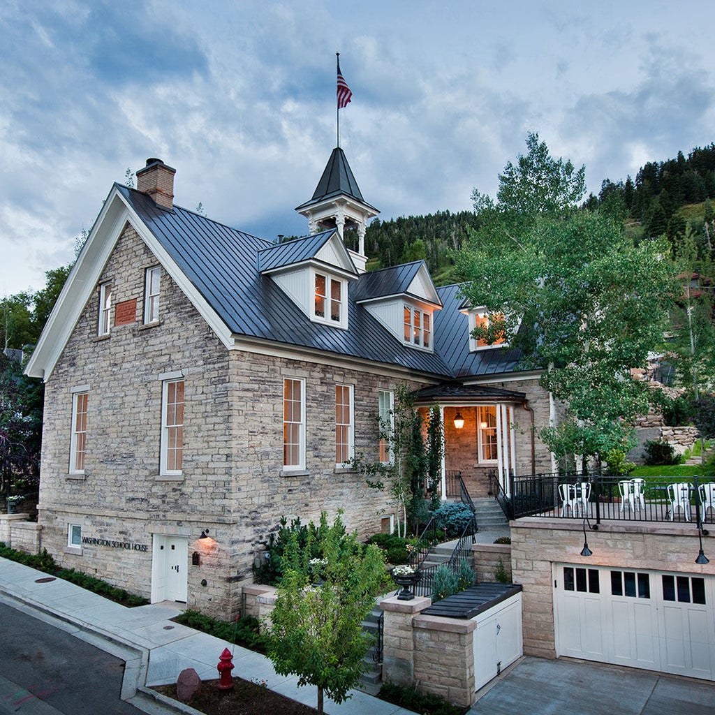 Elegant white stone boutique hotel with classic colonial architecture, featuring tall windows, black shutters and lush winter landscaping