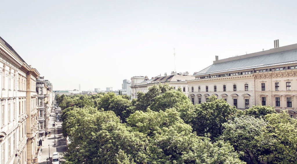 Luxurious baroque-style hotel facade with ornate architectural details, grand white exterior, and elegant windows overlooking Vienna's historic cityscape