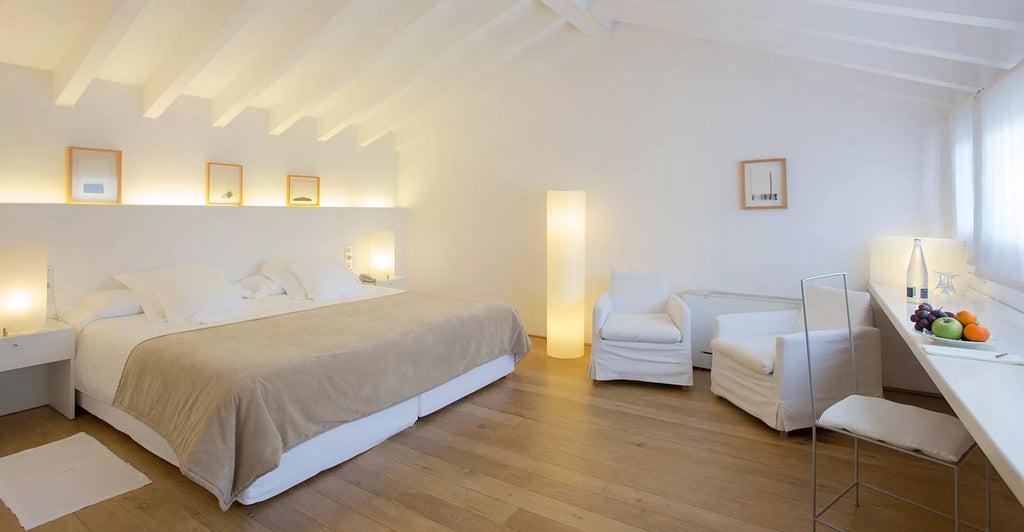 Elegant Doble Deluxe room at Convent de la Missió, featuring soft neutral tones, minimalist decor, and luxurious white linens with Spanish architectural details