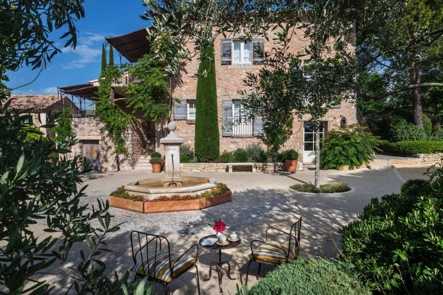 Five-star Provençal hotel with stone buildings and cypress trees nestled in rolling French vineyards at golden sunset