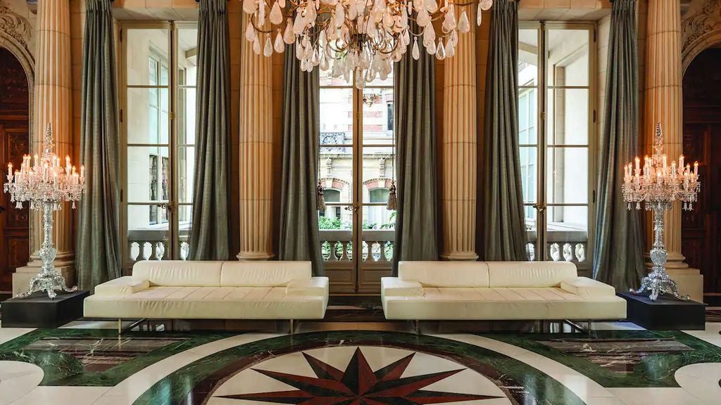 Elegant neoclassical palace hotel with manicured gardens, grand marble staircase and ornate facade illuminated at dusk in Buenos Aires