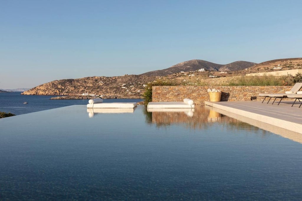 Luxurious white-washed Greek suites with private pools overlooking Oia's blue-domed churches and stunning Aegean Sea sunset panorama in Santorini