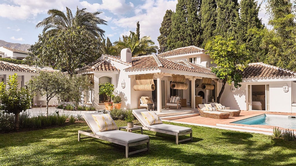 Luxury beachfront resort with white Mediterranean architecture, palm trees, and azure pool overlooking the scenic coastline of southern Spain