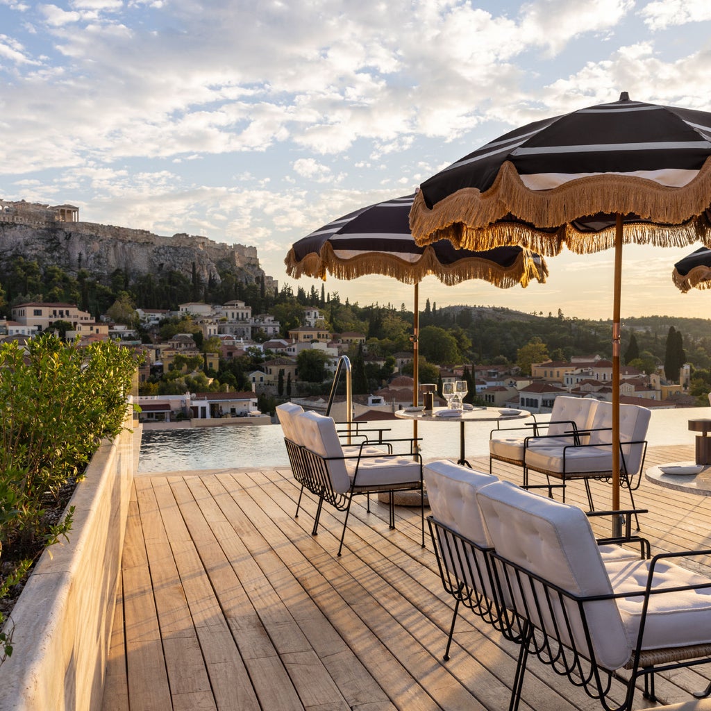 Elegant white-washed Greek hotel with curved architecture, private infinity pools overlooking the Mediterranean Sea at sunset