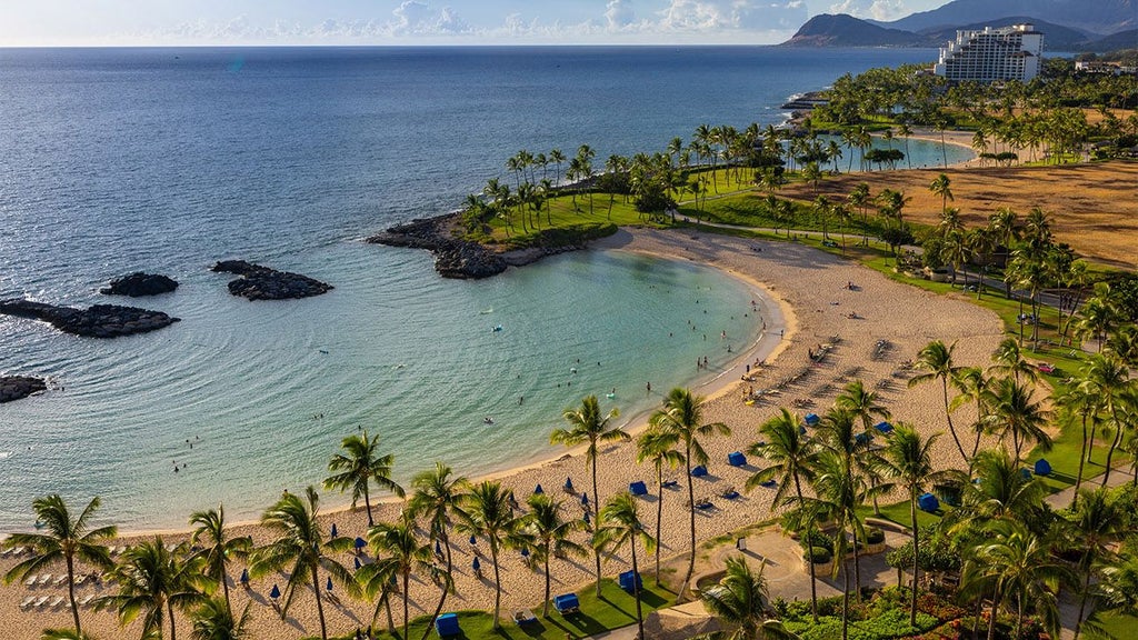 Luxurious beachfront resort with palm trees, crystal-clear waters, infinity pool, and modern Hawaiian-style architecture at scenic Ko Olina coastline.