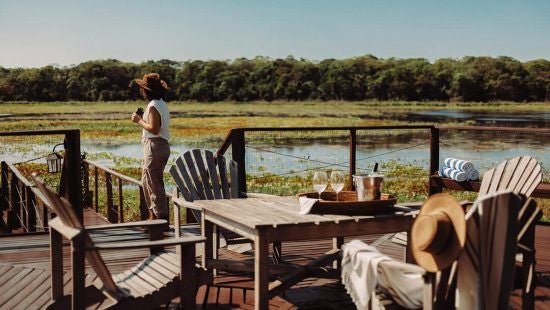 Luxurious private villa bedroom at Caiman Ecological Refuge, featuring elegant decor, large windows overlooking Brazilian wilderness, and sophisticated rustic charm.