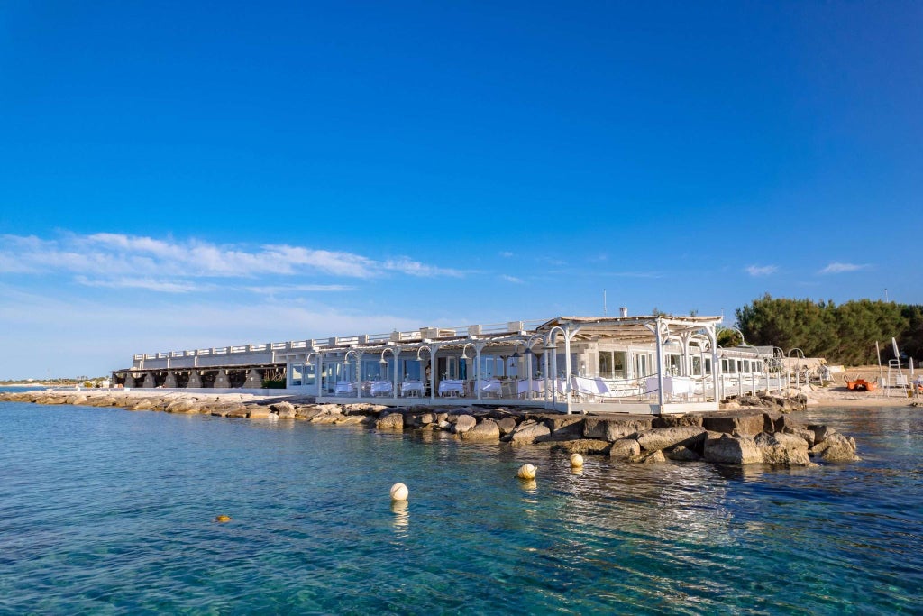 Luxurious Italian seaside resort with elegant blue swimming pool overlooking Adriatic coastline, surrounded by sophisticated modern architecture and lush Mediterranean landscape