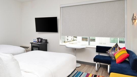 Modern, spacious hotel room with two plush queen beds, sleek contemporary design, minimalist decor, and large window offering ambient natural light at Aloft Charlotte Airport