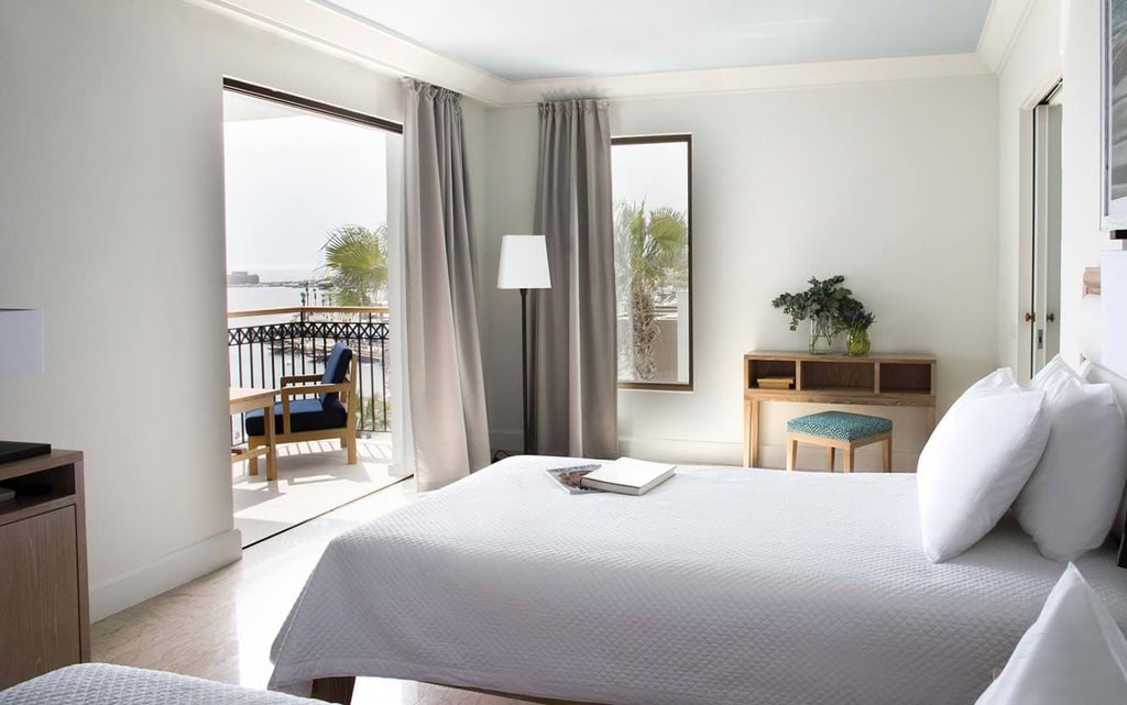 Luxurious sea view hotel room with modern decor, king-sized bed, private balcony overlooking azure Mediterranean waters in Cyprus