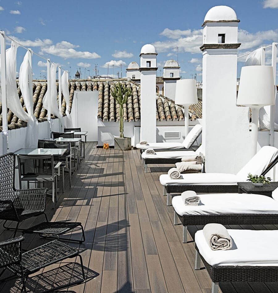 Luxurious whitewashed Spanish colonial courtyard with elegant archways, potted plants, and soft natural light at scenset hotel in Seville