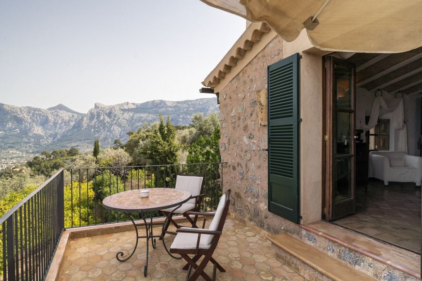 Elegant stone-walled deluxe suite with rustic wooden furnishings, plush white bedding, and panoramic views of Spanish countryside landscape