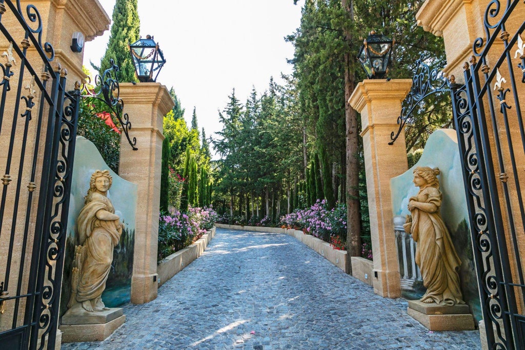 Elegant stone Villa Gallici with lavender-lined pathway, French provincial architecture, blue shutters, and lush gardens in Provence