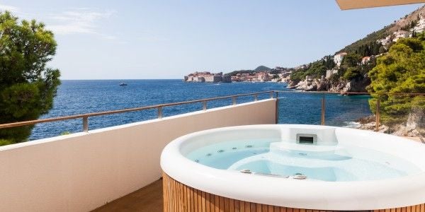 Elegant hotel suite with floor-to-ceiling windows offering panoramic Adriatic Sea views, modern furnishings, and private balcony at Villa Dubrovnik