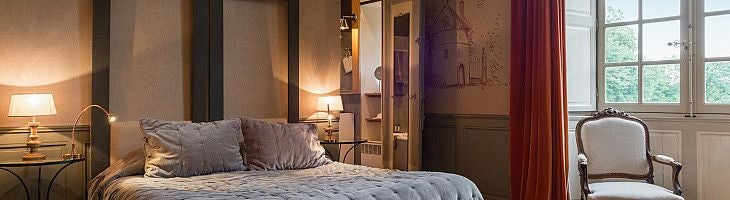 Elegant French château hotel room with soft cream walls, ornate antique furniture, and a private terrace overlooking lush countryside landscape