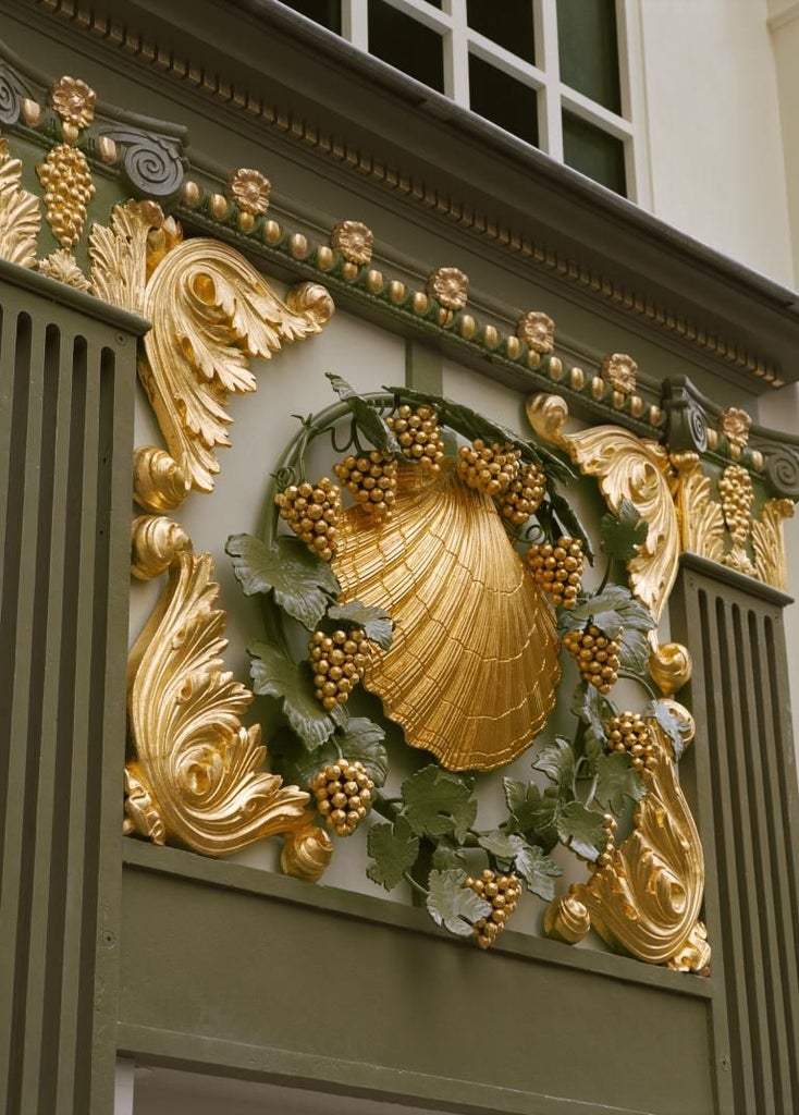 Elegant Parisian luxury hotel with cream-colored facade, intricate wrought-iron balconies, and refined architectural details of French design