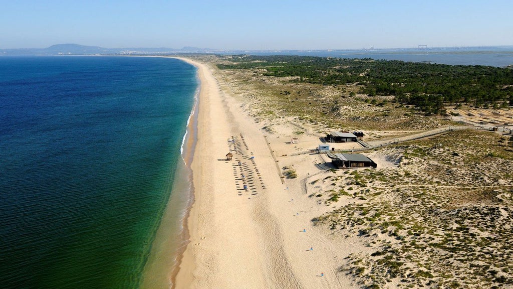 Luxurious eco-friendly resort nestled in Portuguese dunes, featuring minimalist white buildings, natural wood accents, and expansive views of coastal landscape.