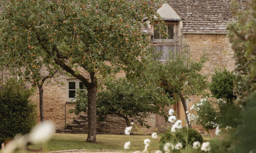 Cozy Gardener's Cottage hotel room with plush white bedding, rustic wood furniture, and soft green accent walls in a charming United Kingdom countryside setting