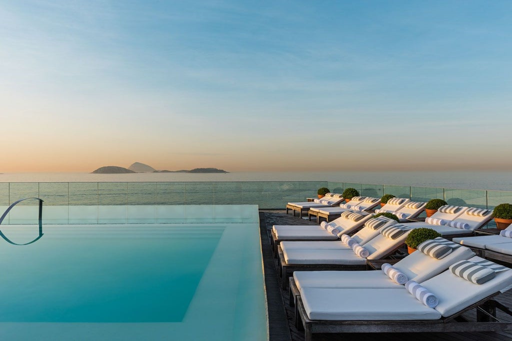 Luxurious rooftop infinity pool overlooking Ipanema Beach, with elegant hotel architecture and Rio de Janeiro's stunning coastline in the background