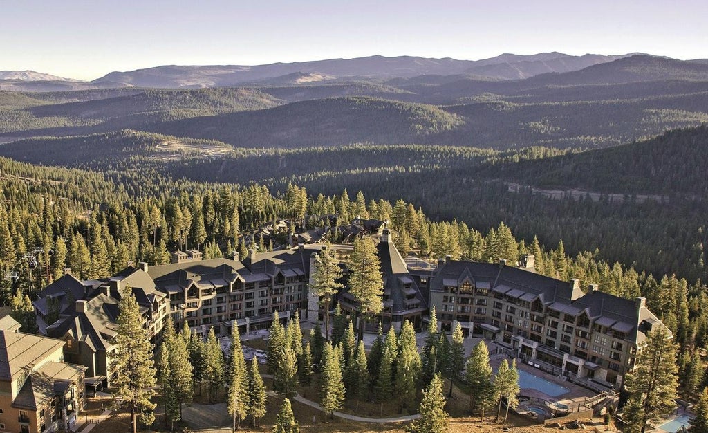 Luxurious mountain resort nestled in snowy Sierra Nevada peaks, featuring stone-and-timber architecture with grand entrance and valet drive