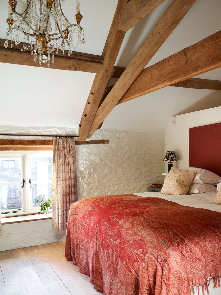 Cozy and elegant cottage suite with plush white bedding, rustic wooden headboard, and soft green accent walls in a tranquil UK countryside retreat