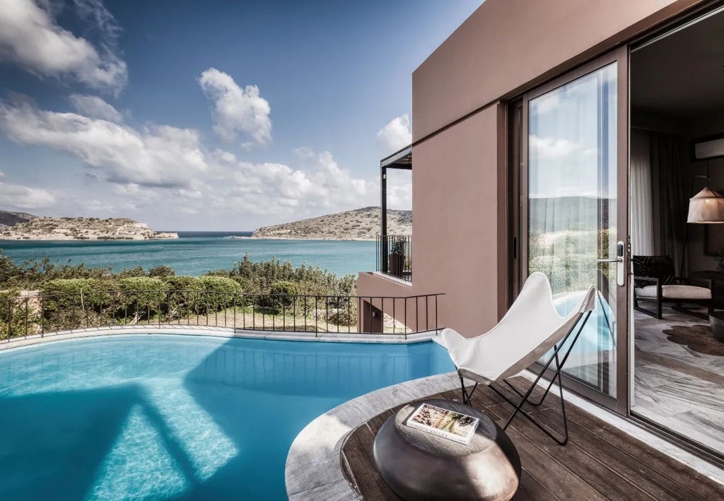 Luxurious beachfront resort in Crete, white domed suites overlooking azure Aegean waters with private infinity pools and palm-lined coastal landscape