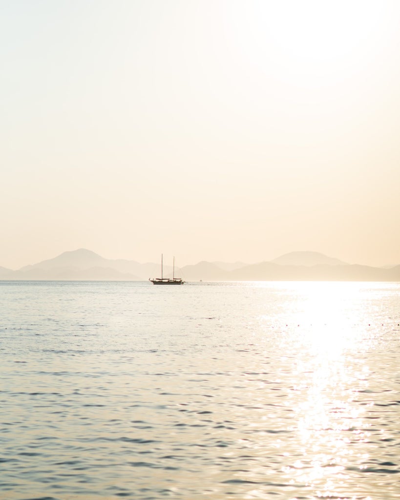 Luxury beach resort in Sardinia with turquoise Mediterranean waters, private cabanas and white sand against dramatic rocky coastline