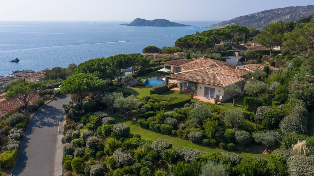 Elegant Mediterranean villa with infinity pool overlooking French Riviera coastline, surrounded by lush gardens and pine trees at sunset