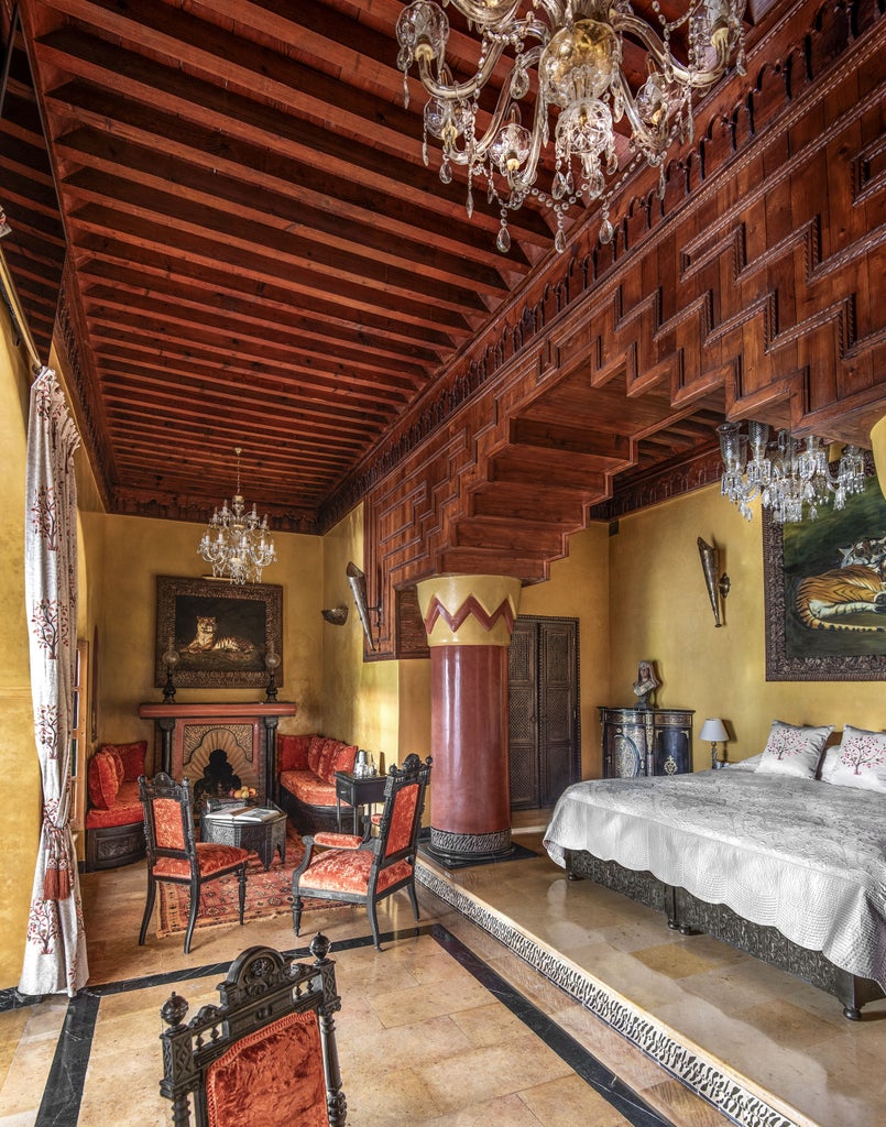 Opulent Moroccan riad hotel with ornate archways, mosaic tiles, and a palm-fringed courtyard pool reflecting traditional architecture