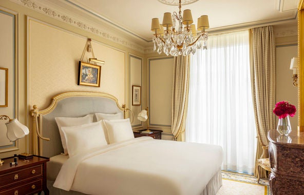 Opulent Parisian suite with crystal chandelier, gilded mirrors, antique furnishings, and Louis XV-style seating in cream and gold tones