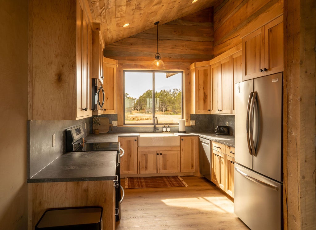 Rustic lodge room with wooden furnishings, plush bedding, and large windows overlooking rugged mountain landscape at Scenset Mountain Ranch accommodation