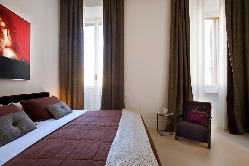 Elegant modern hotel room near Piazza di Spagna, featuring plush white bedding, marble-toned walls, and chic minimalist Italian design aesthetic