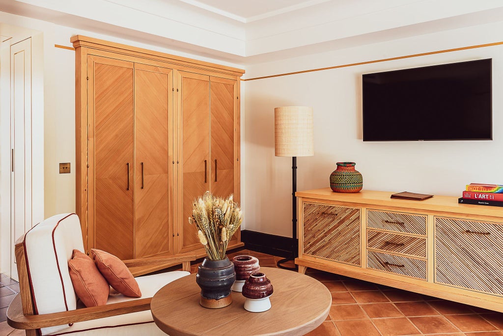 Elegant deluxe junior suite at Lou Pinet hotel with plush white bedding, soft neutral tones, contemporary French styling, and luxurious natural light.