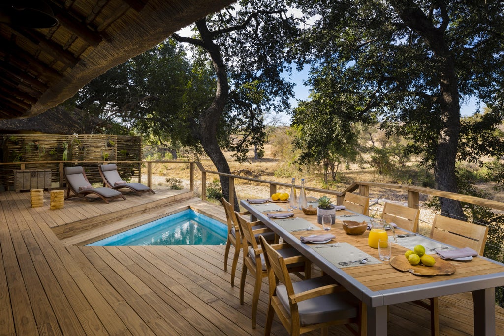 Elevated luxury safari lodge perched atop ancient rock formations, overlooking vast African savanna with infinity pool and viewing deck