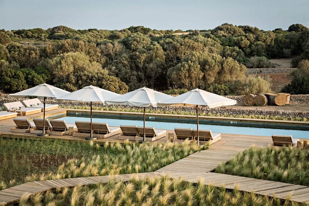 Luxurious historic stone tower hotel with Mediterranean coastline, terracotta rooftops, and golden sunset illuminating ancient Spanish architectural details