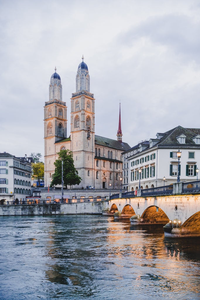 Elegant boat gliding on Lake Zurich with Swiss Alps backdrop, pristine waters reflecting historic cityscape and luxurious waterfront architecture