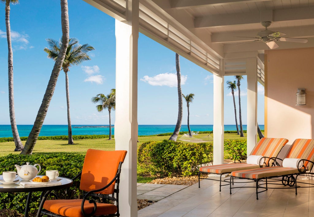 Ocean-front luxury resort with white colonial architecture, swaying palm trees and turquoise waters, featuring private beach cabanas