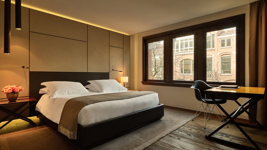 Luxurious two-bedroom suite overlooking Amsterdam, with modern design, floor-to-ceiling windows, contemporary furnishings, and warm wooden accents.