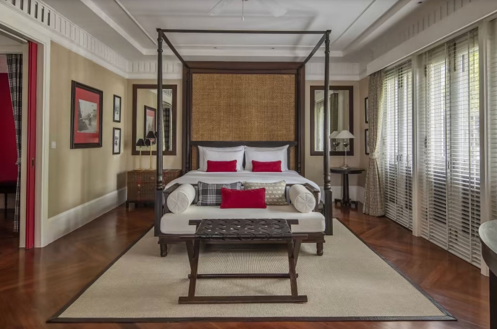 Elegant colonial-style suite with teakwood floors, vintage furnishings, and private terrace overlooking tropical gardens and infinity pool