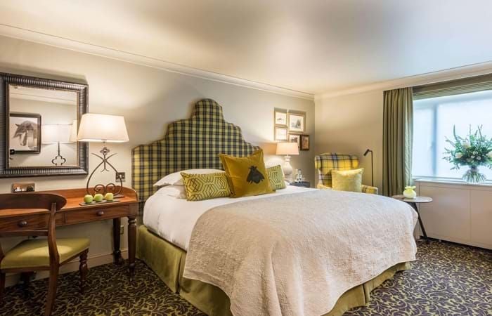 Elegant cozy double room at The Lygon Arms, featuring warm wood furnishings, soft neutral tones, and plush bedding in a charming UK boutique hotel setting