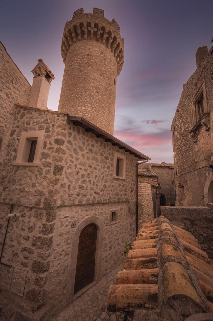 Rustic stone hotel nestled in scenic Italian hillside, with traditional architecture, warm terracotta roofs, and historic charm of Sextantio Albergo Diffuso