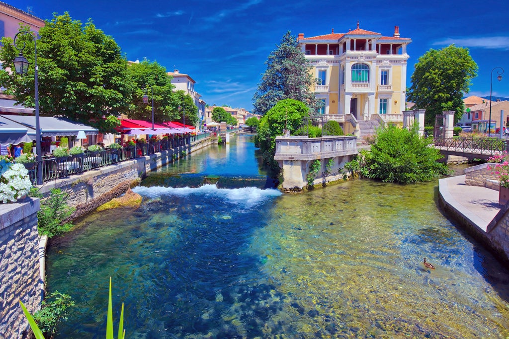 Rustic stone village perched on hillside in Provence, with lavender fields and vineyards stretching across sun-drenched Luberon Valley