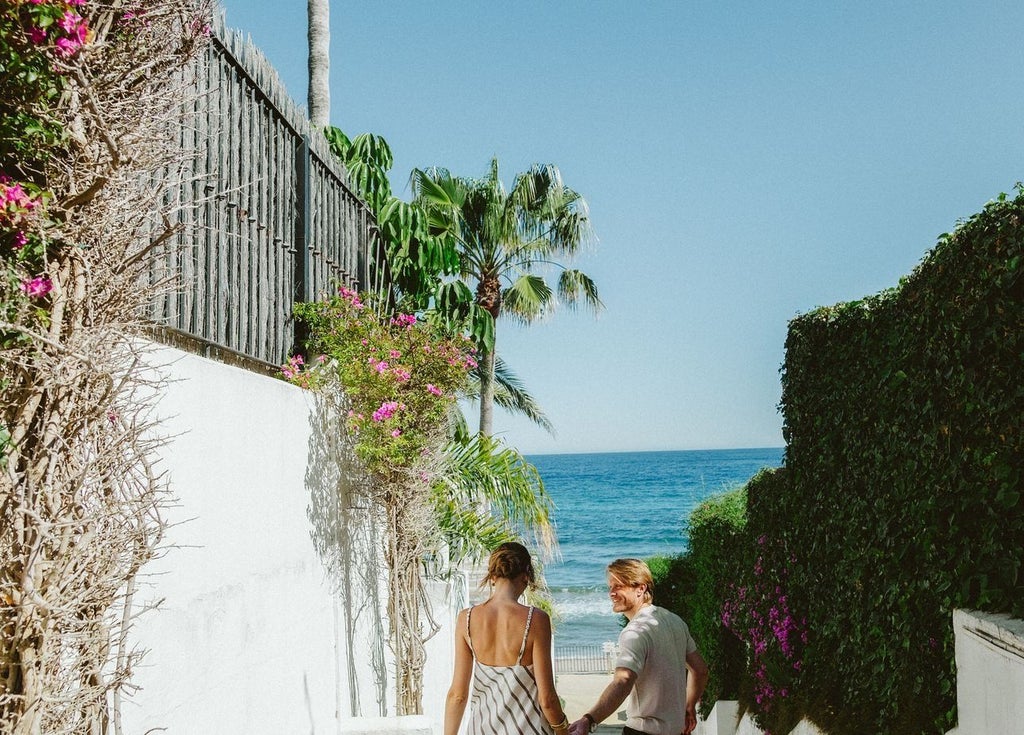 Luxurious white-walled Nobu Hotel terrace in Marbella, with sleek modern furniture, azure pool, and lush tropical palm trees under bright Spanish sunlight