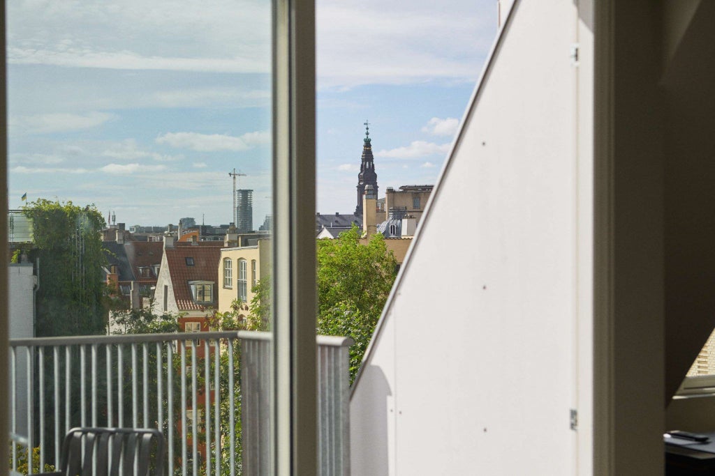 Elegant Danish hotel facade with classic architecture, ornate windows, and pristine white exterior overlooking a charming cobblestone street in Copenhagen's historic district