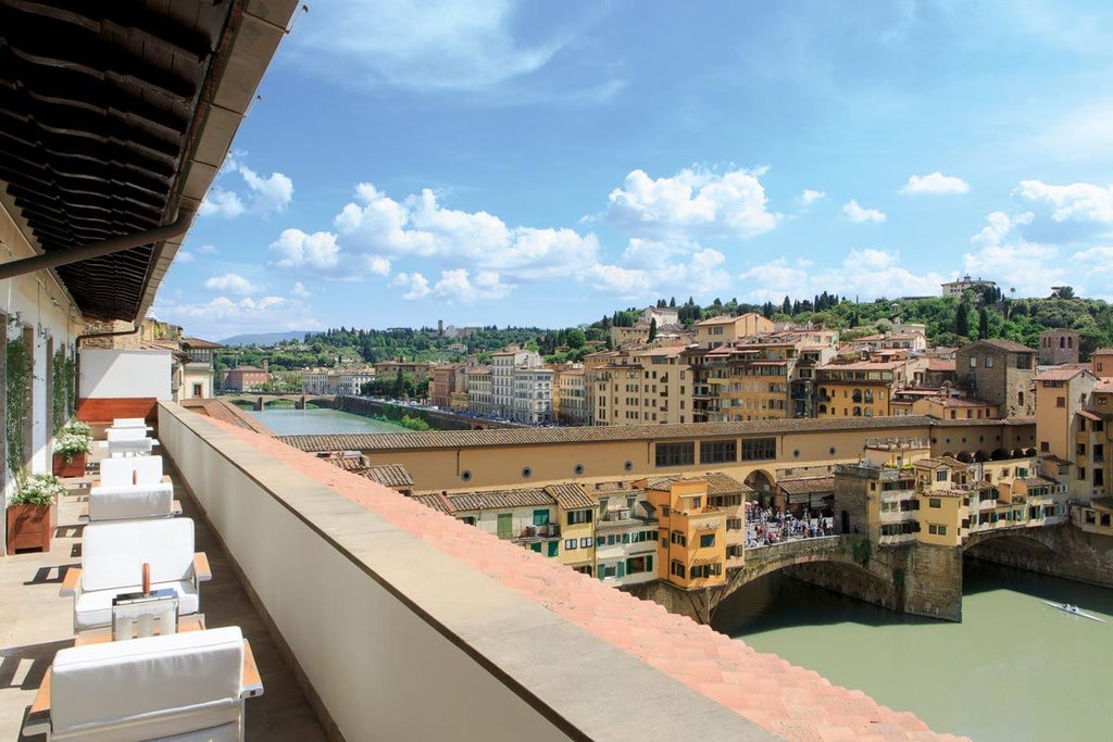 Elegant riverside hotel in Florence with classic stone facade, arched windows, and ornate balconies overlooking the Arno River at sunset