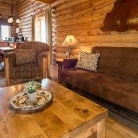 Rustic wooden interior of a 2-bedroom cabin at Zion Mountain Ranch with warm lighting, cozy furnishings, and panoramic mountain views through large windows